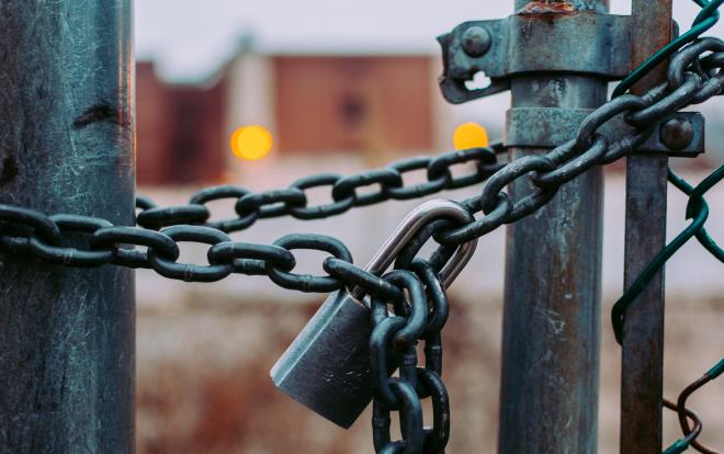 A photo of a locked gate with padlock and chain.